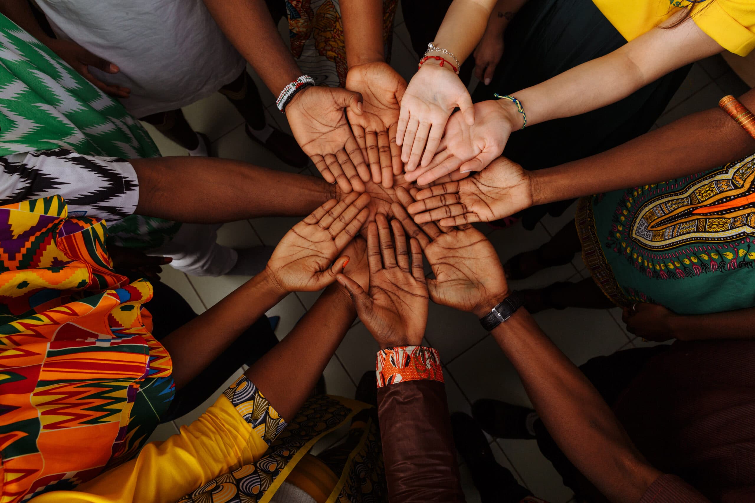 A circle of diverse hands meeting in the centre
